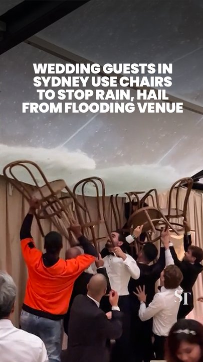 Wedding guests in Sydney use chairs to stop rainwater from flooring outdoor venue amid severe storm